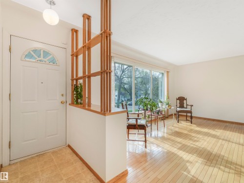 Front entry with a decorative half-moon window, tiled flooring, and a wood slat room divider - 12614 69 Street Nw, Edmonton, AB 