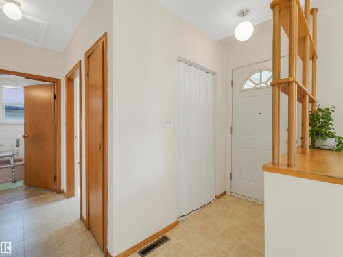 Entryway featuring tiled flooring, a white front door with an arched window, and a built-in wood-toned room divider - 12614 69 Street Nw, Edmonton, AB 