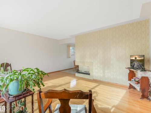 Hardwood flooring, white painted walls, textured accent wall, and a built-in fireplace with a brick surround - 12614 69 Street Nw, Edmonton, AB 