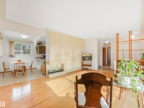 Hardwood flooring, a prominent fireplace with a white brick surround, and a built-in shelving unit - 12614 69 Street Nw, Edmonton, AB 
