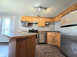 Kitchen featuring wood-finish cabinetry, stainless steel appliances, and a central island with an extended countertop - 