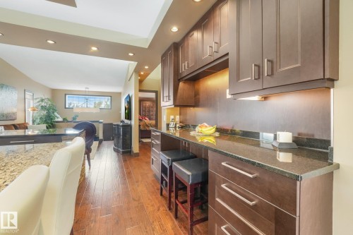 Wood-finish flooring, dark wood cabinetry, granite countertops, recessed lighting, and a tray ceiling - 12827 150 Avenue Nw, Edmonton, AB 