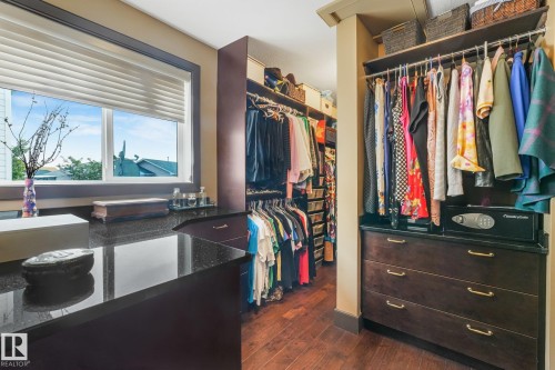 Custom closet system featuring built-in cabinetry, polished dark countertops, ample hanging storage, and rich wood-finish flooring - 12827 150 Avenue Nw, Edmonton, AB 