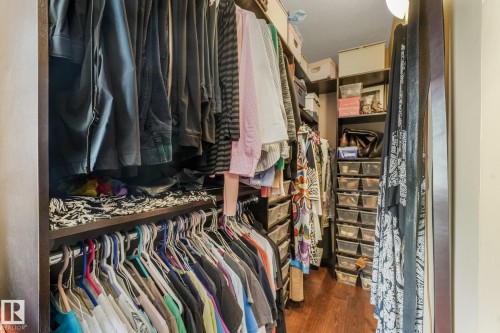 Custom closet organization system with dark wood-finish shelving and hanging rods - 12827 150 Avenue Nw, Edmonton, AB 