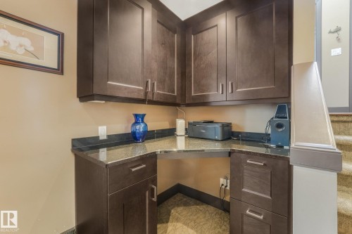 Built-in desk area with dark wood cabinetry and a stone countertop - 12827 150 Avenue Nw, Edmonton, AB 