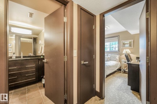 Dark wood-finish doors with brushed nickel hardware, bathroom featuring a dark wood-finish vanity with drawer storage and a dark countertop, tile flooring, and a framed mirror - 12827 150 Avenue Nw, Edmonton, AB 
