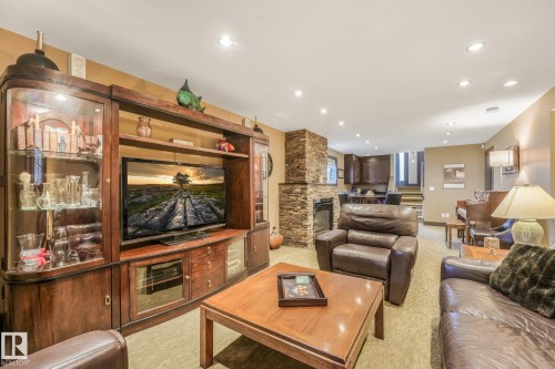 Recessed lighting, stacked stone fireplace, built-in media cabinetry, wood-finish coffee table, and wood-finish side table - 12827 150 Avenue Nw, Edmonton, AB 