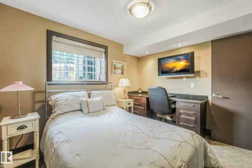 Recessed lighting, built-in desk with stone-finish countertop, wood-finish cabinetry, mounted television, and a window with blinds - 12827 150 Avenue Nw, Edmonton, AB 