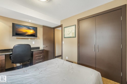Built-in desk with dark countertop, integrated cabinetry, and wall-mounted television - 12827 150 Avenue Nw, Edmonton, AB 