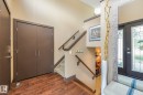 Warm wood-finish flooring, built-in double-door closet, carpeted staircase with wood handrails, and a leaded glass entry door - 12827 150 Avenue Nw, Edmonton, AB 