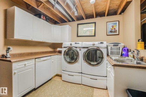 Laundry area featuring white cabinetry, a built-in sink, and extensive counter space - 12827 150 Avenue Nw, Edmonton, AB 