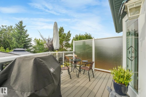 Deck featuring composite wood-finish flooring, glass panel railing, and privacy screen - 12827 150 Avenue Nw, Edmonton, AB 