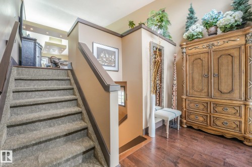 Carpeted staircase with dark wood-finish handrail, wood-finish flooring, and recessed ceiling lighting - 12827 150 Avenue Nw, Edmonton, AB 