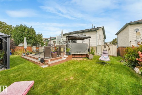 Expansive backyard featuring a multi-level deck, lush green lawn, and privacy fencing - 12827 150 Avenue Nw, Edmonton, AB 