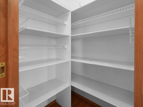 Corner pantry featuring white shelving, wire racks, and wood-finish flooring - 535 Pardee Bay Nw, Edmonton, AB 