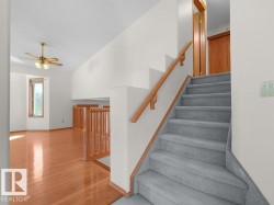 Carpeted staircase with wood railing, warm wood-finish flooring, and natural light from a window - 