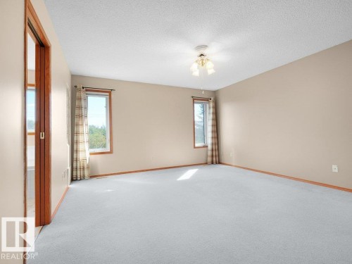 Neutral wall color, light-colored carpeting, two windows, wood-finish trim, and a ceiling fan with integrated lighting - 535 Pardee Bay Nw, Edmonton, AB 