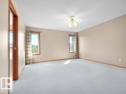 Neutral wall color, light-colored carpeting, two windows, wood-finish trim, and a ceiling fan with integrated lighting - 