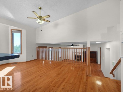 Vaulted ceiling with ceiling fan, wood-finish flooring, wood-finish railing, and a window with wood trim - 535 Pardee Bay Nw, Edmonton, AB 