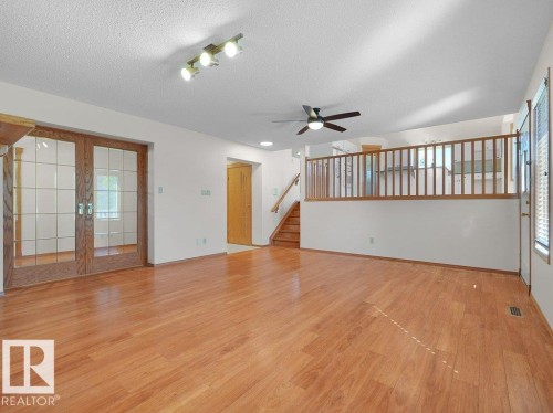 Wood-finish flooring, recessed lighting, ceiling fan, wood-frame glass panel doors, and wood railing - 535 Pardee Bay Nw, Edmonton, AB 