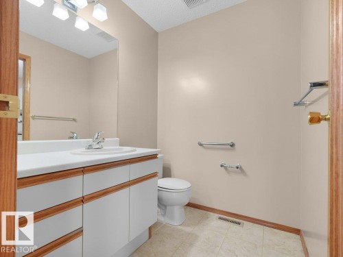 Vanity with integrated sink, wood-finish cabinetry, and neutral wall color - 535 Pardee Bay Nw, Edmonton, AB 
