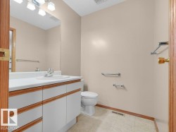 Vanity with integrated sink, wood-finish cabinetry, and neutral wall color - 