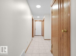 Hallway with tiled flooring, recessed lighting, and wood-panel doors - 