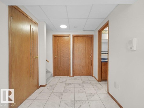 Tile flooring with geometric pattern, wood-finish doors, dropped ceiling, recessed lighting, and wall-mounted intercom system - 535 Pardee Bay Nw, Edmonton, AB 