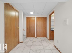Tile flooring with geometric pattern, wood-finish doors, dropped ceiling, recessed lighting, and wall-mounted intercom system - 