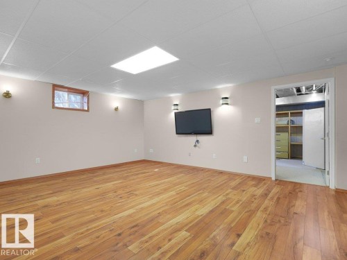 Wood-finish flooring, recessed ceiling lighting, wall-mounted sconces, and a paneled drop ceiling - 535 Pardee Bay Nw, Edmonton, AB 