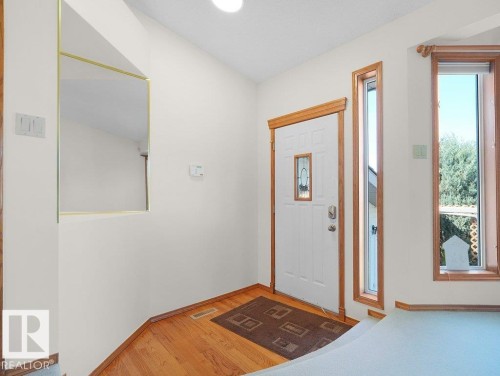 Entryway with wood-finish flooring, white paneled door with decorative glass insert, and natural wood trim accents - 535 Pardee Bay Nw, Edmonton, AB 