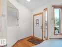 Entryway with wood-finish flooring, white paneled door with decorative glass insert, and natural wood trim accents - 535 Pardee Bay Nw, Edmonton, AB 