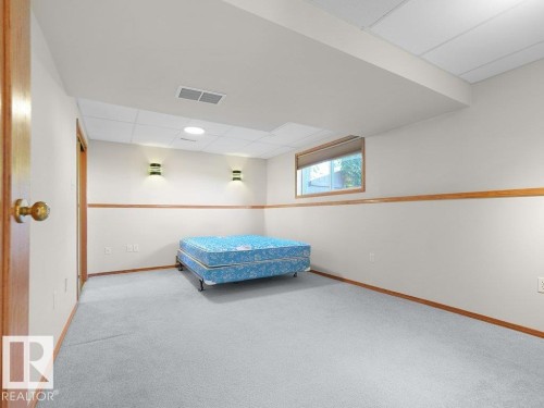 Fourth bedroom - Carpeted room featuring a drop ceiling, wall sconces, wood-trim window, and wood-paneled doors - 535 Pardee Bay Nw, Edmonton, AB 
