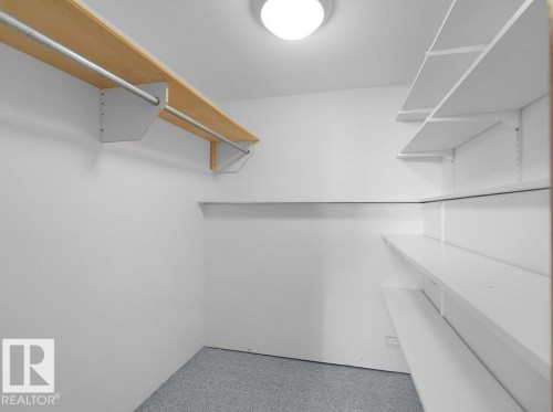 Recessed ceiling light fixture, wood-finish shelving with hanging rods, adjustable white shelving system, and grey carpet flooring - 535 Pardee Bay Nw, Edmonton, AB 