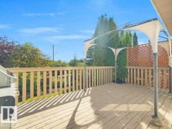 Expansive wood deck with a privacy fence and a white fabric gazebo, surrounded by mature greenery - 