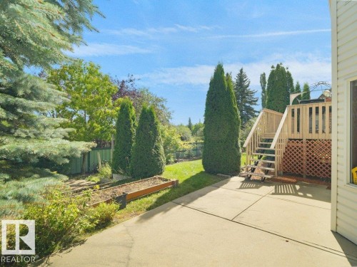 Expansive backyard with a manicured lawn, concrete patio, and a wood-finish deck with stairs - 535 Pardee Bay Nw, Edmonton, AB 