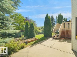 Expansive backyard with a manicured lawn, concrete patio, and a wood-finish deck with stairs - 