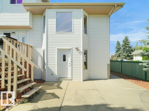 White horizontal siding exterior with a large upper-level window and a lower-level entry door - 535 Pardee Bay Nw, Edmonton, AB 