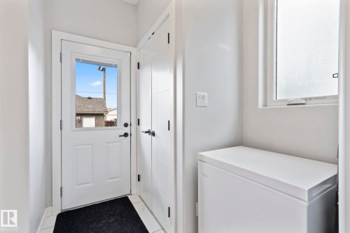 White paneled exterior door with glass insert, black hardware, and tiled flooring - 10338 162St Nw, Edmonton, AB 