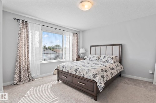 Wall-to-wall carpeting with light-toned walls, a flush-mount ceiling light, and a large window with blinds - 10338 162St Nw, Edmonton, AB 