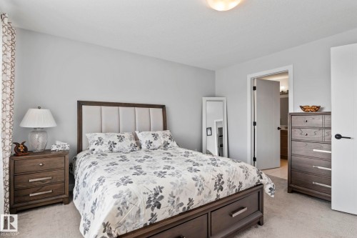 Neutral wall color, soft carpeting, recessed panel headboard, dark wood-finish nightstand, built-in ceiling light fixture - 10338 162St Nw, Edmonton, AB 
