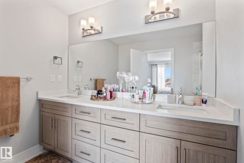 Dual vanity with integrated sinks, light wood-finish cabinetry, and brushed nickel hardware - 10338 162St Nw, Edmonton, AB 