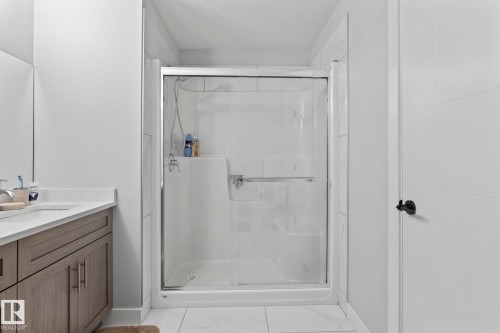 Shower enclosure with sliding glass doors, integrated shelving, and a grab bar - 10338 162St Nw, Edmonton, AB 