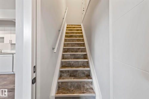 Staircase with tile risers and treads, featuring a white handrail - 10338 162St Nw, Edmonton, AB 