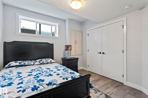 Wood-finish flooring with white trim, built-in dual-door closet, and an overhead light fixture - 10338 162St Nw, Edmonton, AB 