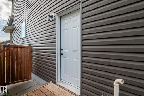 Brown horizontal siding with white trim, featuring a white paneled door with black hardware - 10338 162St Nw, Edmonton, AB 