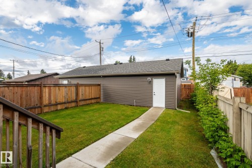 Detached garage with dark grey horizontal siding and a white side entry door - 10338 162St Nw, Edmonton, AB 