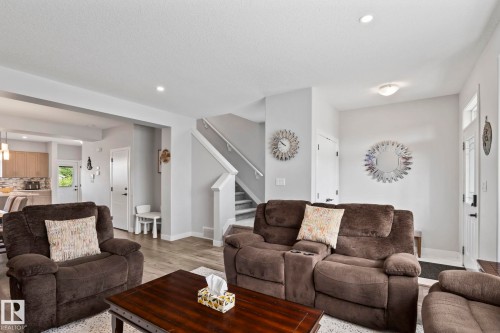 Recessed lighting, wood-finish flooring, a contemporary staircase, and a kitchen with light wood cabinetry and a tiled backsplash - 10338 162St Nw, Edmonton, AB 