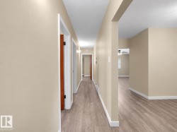 Hallway with wood-finish flooring, light neutral wall tones, and white trim - 