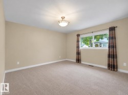 Neutral-toned walls, carpet flooring, a window with exterior visibility, and an overhead light fixture - 